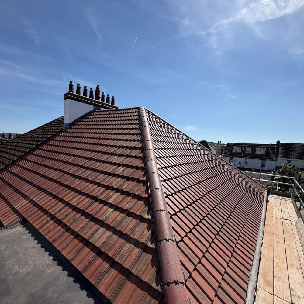 New tiles on a pitched roof with the chimney stack repointed
