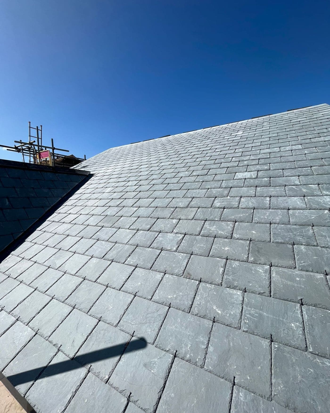 A slate roof completed by Goldsmith Roofing, photographed from the scaffold against a blue sky