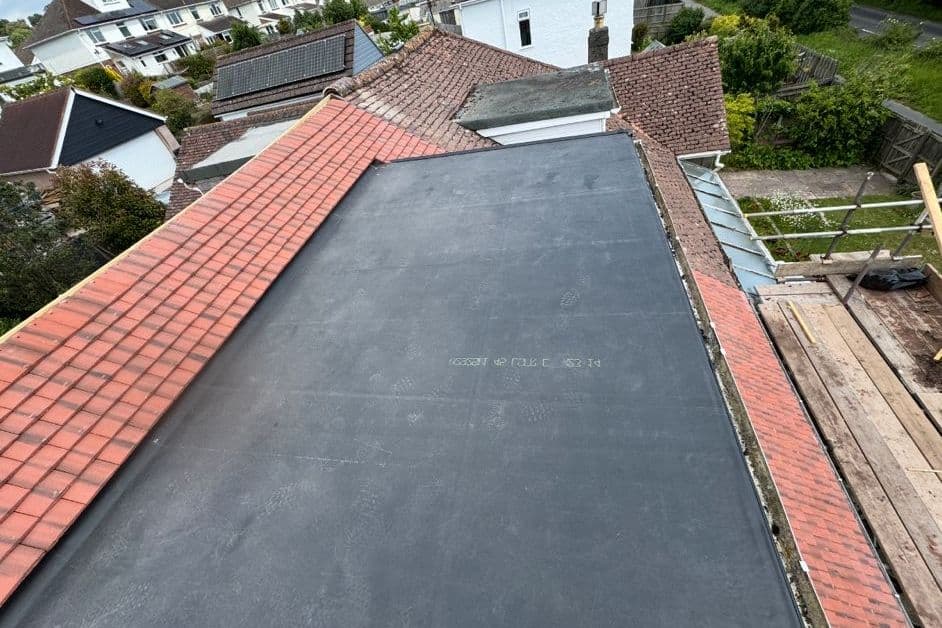 A newly laid rubber flat roof next to a tiled pitched roof