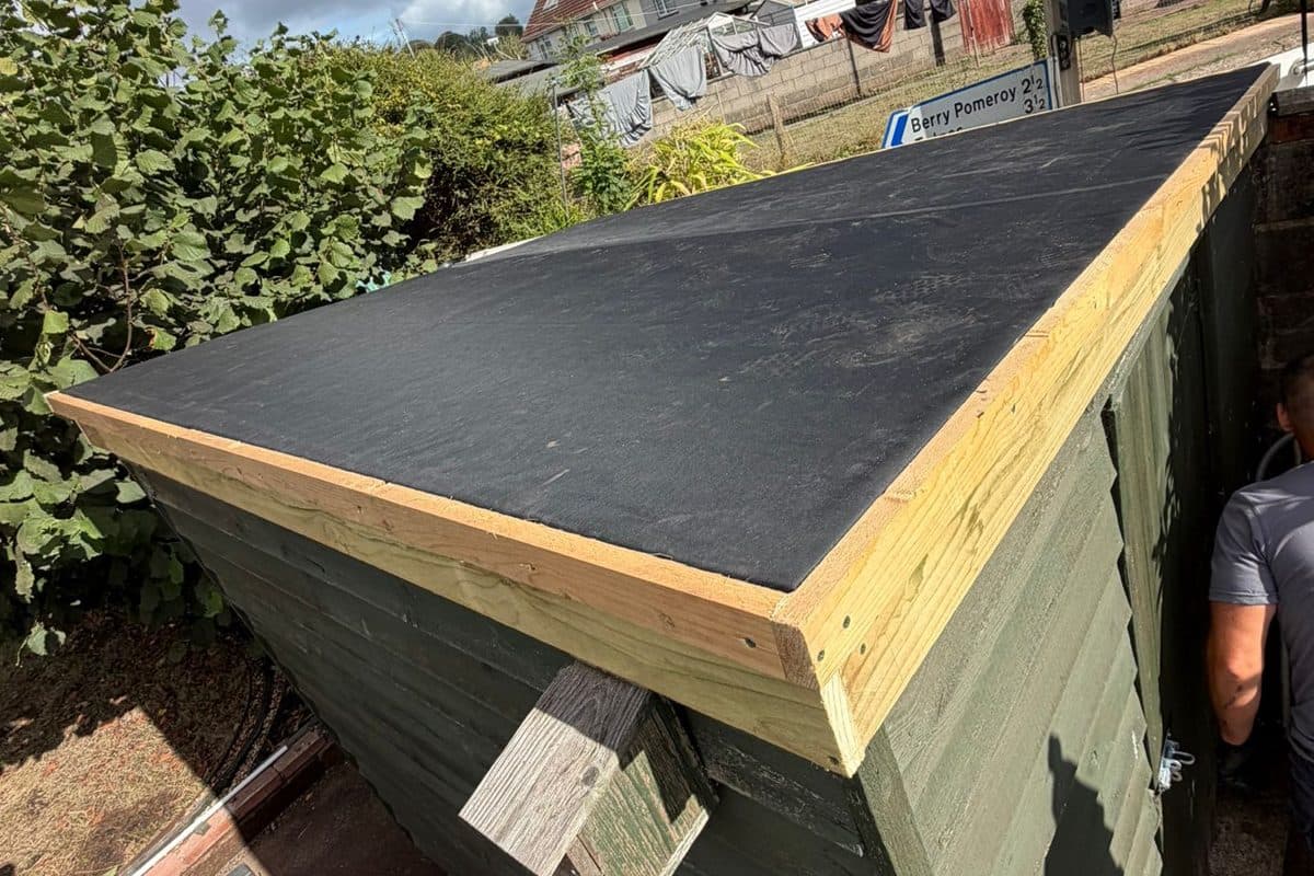 A garden shed with a newly laid flat roof and fresh timber trim